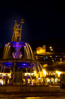 Plaza de Armas fountain at night with Church of San Cristobal on hillside behind the plaza